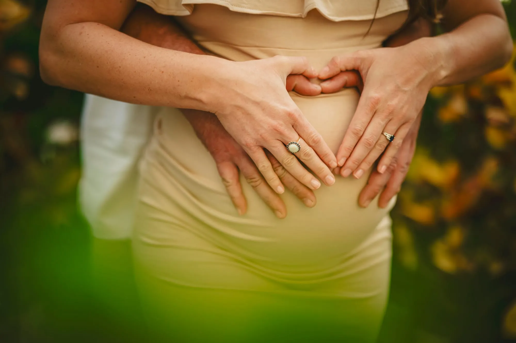 Couple's hands forming heart shape on baby bump, fertility and prenatal nutrition support by LifeBloom Nutrition
